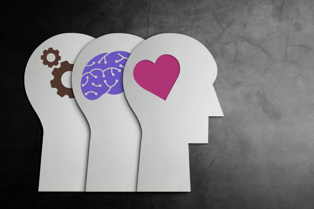 Ilustração de três perfis humanos com ícones de engrenagens, cérebro e coração a representar competências cognitivas e emocionais.